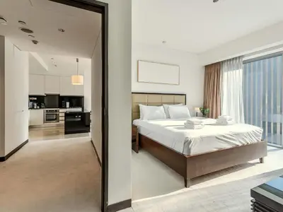 a bedroom with a large bed and a kitchen at Incredible Views at The Address Dubai Marina 1BR in Dubai