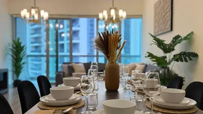 a dining room with a long table with plates and glasses at ASHRI HH | Elegant 2 BHK| Downtown Dubai | 8Blvd in Dubai