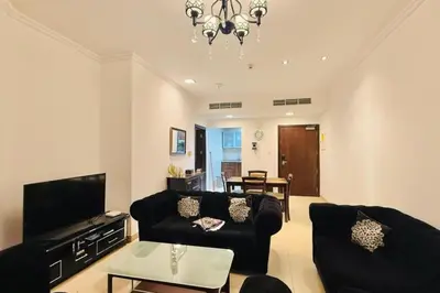 a living room with black furniture and a chandelier at Cosy 1 Bed in JLT in Dubai