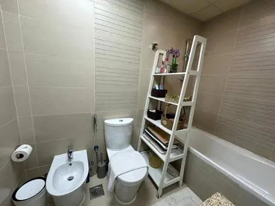 a bathroom with a toilet and a white shelf at Cosy 1 Bed in JLT in Dubai
