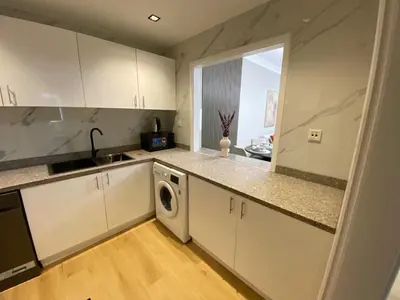 a kitchen with white cabinets and a washer and dryer at Comfy 1 Bedroom in Dubai Marina in Dubai
