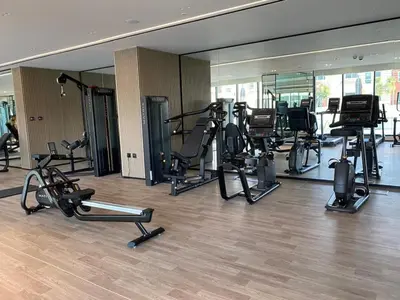 a gym with several treadmills and elliptical machines at Large 1 Bedroom Apartment in Azizi Riviera 15 in Dubai