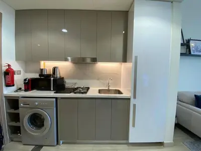 a kitchen with a sink and a washing machine at Modern Studio with Balcony - Pool View in Dubai