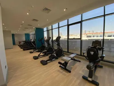 a row of exercise bikes in a gym with windows at Bright Studio - Azizi Riviera 35 - Fully Furnished in Dubai