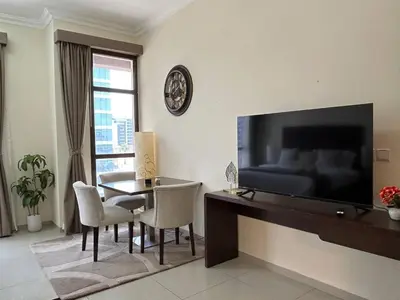 a living room with a table and a large television at Modern Studio - Lincoln Park West - Dubai, Arjan in Dubai