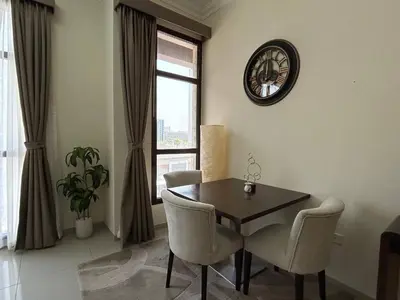 a dining room with a table and chairs and a clock at Modern Studio - Lincoln Park West - Dubai, Arjan in Dubai