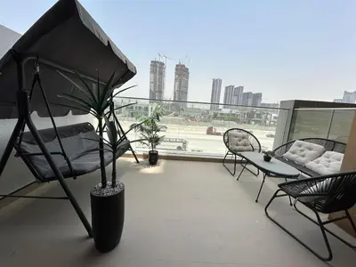 a balcony with a chair and a table and a plant at Stylish Studio Retreat, Meydan Area and Pool Access in Dubai