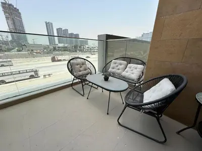 three chairs and a table on a balcony with a view at Stylish Studio Retreat, Meydan Area and Pool Access in Dubai