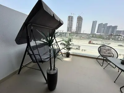 a balcony with a chair and a plant and a window at Stylish Studio Retreat, Meydan Area and Pool Access in Dubai