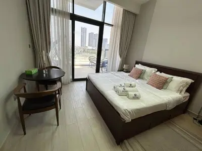 a bedroom with a bed and a table and a window at Stylish Studio Retreat, Meydan Area and Pool Access in Dubai