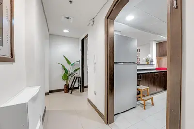 a kitchen with white walls and a wooden door at Luxury 2BR Escape - Durar 1B 2, Wadi Al Safa in Dubai
