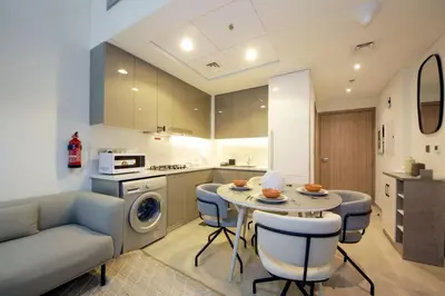 a kitchen and living room with a table and chairs at Chic Riviera 27 - 1BHK - Pool , Gym , Parking in Dubai
