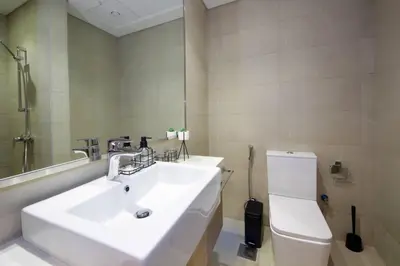 a bathroom with a white sink and a toilet at Chic Riviera 27 - 1BHK - Pool , Gym , Parking in Dubai
