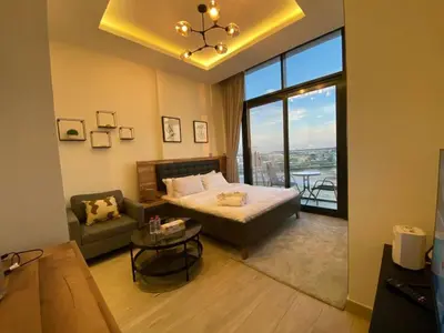 a bedroom with a bed and a couch and a window at Modern Studio in Azizi Riviera 10, Near Downtown in Dubai