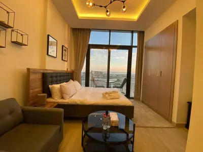 a bedroom with a bed and a living room with a couch at Modern Studio in Azizi Riviera 10, Near Downtown in Dubai