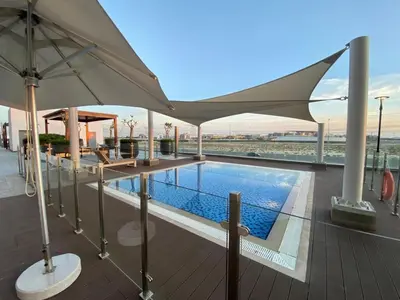 a swimming pool with umbrellas on top of a building at Modern Studio in Azizi Riviera 10, Near Downtown in Dubai