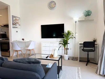 a living room with a couch and a tv on a wall at ASHRI HH | Elegant Studio | UNA Townsquare in Dubai