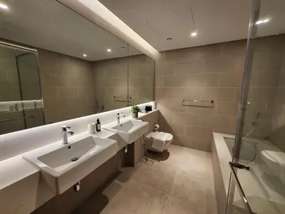 a bathroom with two sinks and a shower and a toilet at SOLARTE Luxe - NEW Canal Front Residence - Pool with Burj Views in Dubai