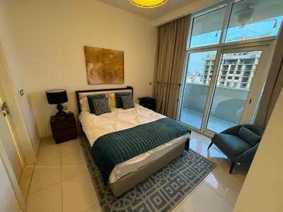 a bedroom with a bed and a chair and a window at Premium 1BR Apartment In Damac Ghalia with City View & Balcony in Dubai