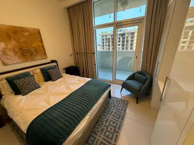 a bedroom with a bed and a chair and a window at Premium 1BR Apartment In Damac Ghalia with City View & Balcony in Dubai