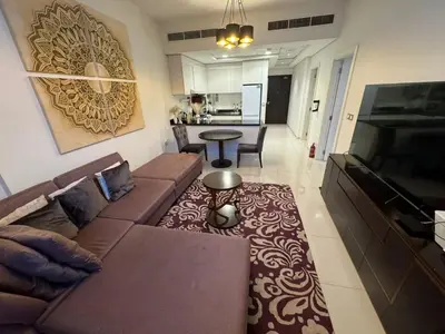 a living room with a brown couch and a kitchen at Premium 1BR Apartment In Damac Ghalia with City View & Balcony in Dubai
