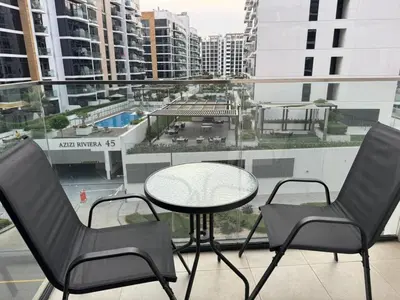 a table and chairs on a balcony with a view of a city at Azizi Riviera 41 - Meydan by Golden Casa in Dubai