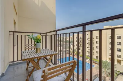 a balcony with a table and a bench and a pool at Remraam, 1 Bedroom in Al Ramth 11 - Allsopp & Allsopp in Dubai