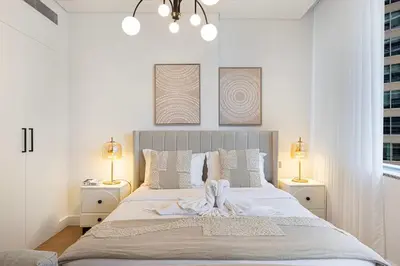 a white bedroom with a large bed with two lamps at DIFC Sky Gardens Studio In front of DIFC Gate in Dubai