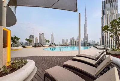 a group of lounge chairs on a deck with a view of a city at Luxury 3BR Imperial Avenue Burj Khalifa Views in Dubai