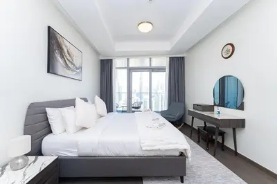 a bedroom with a bed and a desk and a window at Luxury 3BR Imperial Avenue Burj Khalifa Views in Dubai
