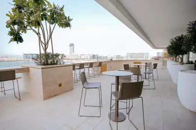 a bar on the roof of a building with chairs and tables at Cozy Apartment with Private Beach & Palm Views in Dubai