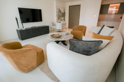 a living room with a white couch and chairs at Cozy Apartment with Private Beach & Palm Views in Dubai