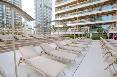 a row of white lounge chairs on a building at Cozy Apartment with Private Beach & Palm Views in Dubai