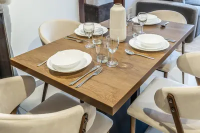 a wooden table with plates and wine glasses on it at RH - Burj Khalifa view with large balcony, 02BR retreat in business bay in Dubai