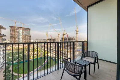 a balcony with two chairs and a view of a city at Gym, Spa & Sauna, Pool, Tenis Court, Dishwasher, 2BR in Central Park in Dubai