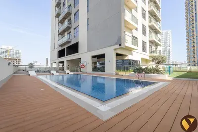 a swimming pool in front of a building at Vogue JVC Jeewar Tower Near Circle Mall, One Bedroom Apartment with Balcony and City View, Access to all Amenities in Dubai
