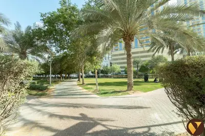 a sidewalk with palm trees in front of a building at Vogue JVC Jeewar Tower Near Circle Mall, One Bedroom Apartment with Balcony and City View, Access to all Amenities in Dubai