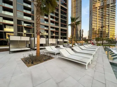 a row of white chaise lounges in a courtyard at Modern 1BR Canal View Pool View in Dubai