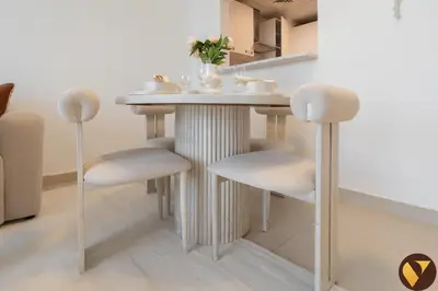 a small table with white chairs in a room at Vogue JVC Jeewar Tower Near Circle Mall, One Bedroom Apartment with Balcony and City View, Access to all Amenities in Dubai