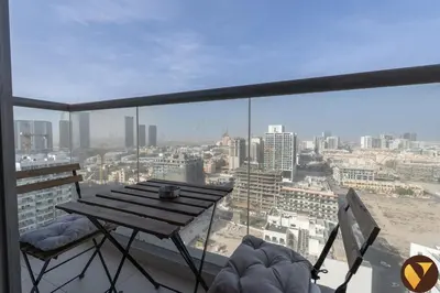 a balcony with a table and a view of a city at Vogue JVC Jeewar Tower Near Circle Mall, One Bedroom Apartment with Balcony and City View, Access to all Amenities in Dubai