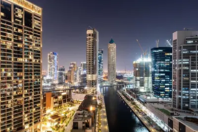 a city skyline at night with a river and buildings at Modern Studio Canal & Pool View Business Bay in Dubai