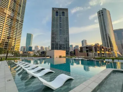 a swimming pool with white lounge chairs in a city at Modern Studio Canal & Pool View Business Bay in Dubai