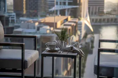 a table with two chairs and coffee cups on a balcony at Frank Porter - Peninsula One in Dubai