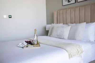 a bed with a bottle of champagne and a tray of fruit at Frank Porter - Peninsula One in Dubai