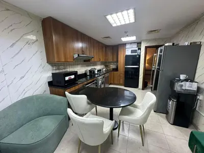 a kitchen with a table and chairs and a refrigerator at Sea View Luxe Room Marina Dubai in Dubai
