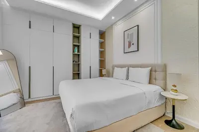 a white bedroom with a large bed and a table at Sadaf 2701 in Dubai