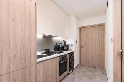 a kitchen with white cabinets and a stove and a door at 2 Apt Combo Studio And 1BR Same Tower Canal View in Dubai
