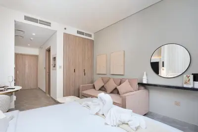 a bedroom with a bed and a couch and a mirror at 2 Apt Combo Studio And 1BR Same Tower Canal View in Dubai