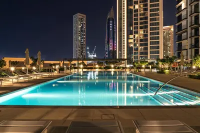 a large swimming pool in a city at night at Burj Khalifa Doorstep Stunning 2BR Apartment in Dubai