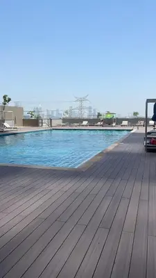 a large swimming pool with a wooden floor and blue water at Holiday heaven specious one bed room apartment near Dubai mall with burj khalifa view in Dubai